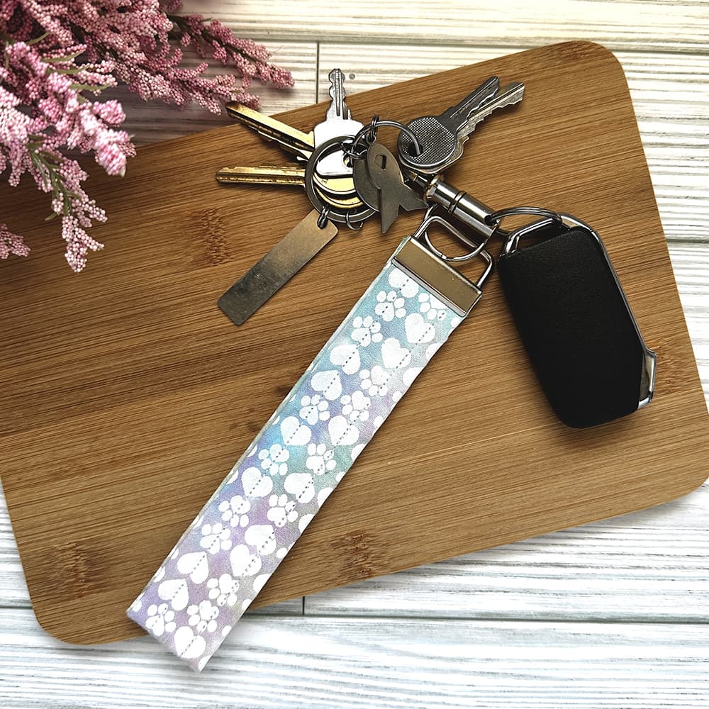 Keychain with floral pattern on a wooden surface with flowers in the background