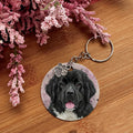 Keychain with a dog's face on a wooden surface with pink flowers
